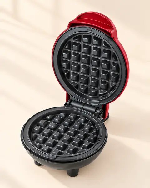 Red Dash mini waffle maker open, showing the round waffle plates